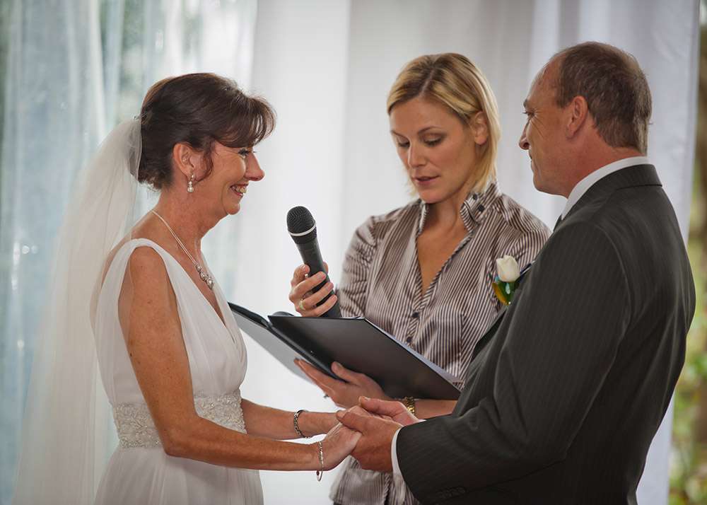 Celebrant with microphone beside the bride and groom