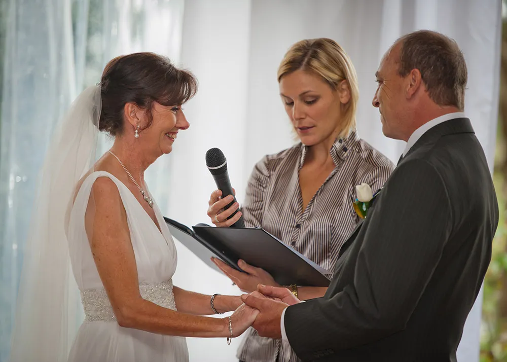 Celebrant with microphone beside the bride and groom